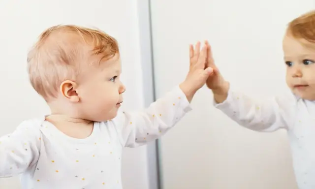 Bambino che tocca il suo riflesso, un momento chiave nella costruzione del sé nel bambino.
