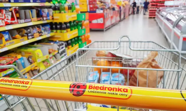 Wózek sklepowy z zakupami w Biedronce, widok z perspektywy klienta.