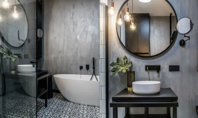 Nowoczesna łazienka w stylu loft z wolnostojącą wanną, umywalką nablatową i betonową ścianą.