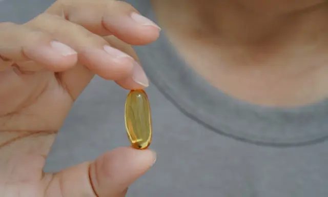 Dłoń trzyma kapsułkę z olejem. Zastanawiasz się nad omega-3 6 9 skutki uboczne?