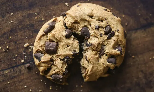 Un cookie aux pépites de chocolat, brisé en deux, révèle sa texture moelleuse. La meilleure recette de cookies pour un goûter gourmand.