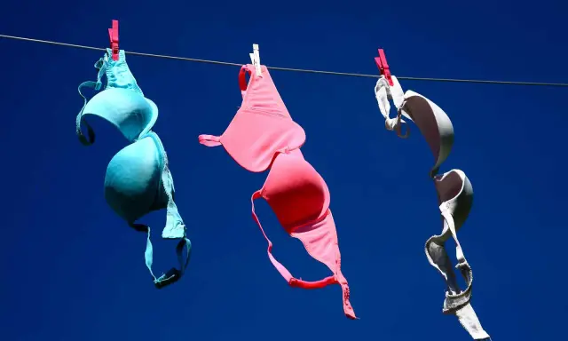 Tre reggiseni colorati (blu, rosa, bianco) stesi ad asciugare al sole. Forse non portare il reggiseno fa crescere il seno, ma l'aria aperta li fa asciugare bene!