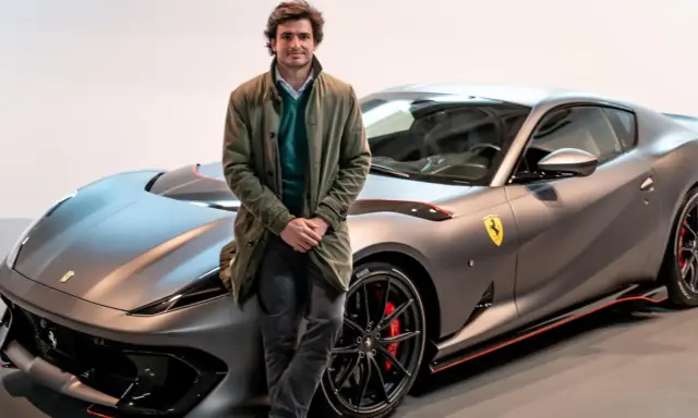 Carlos Sainz posa junto a un Ferrari gris mate, listo para la próxima carrera.