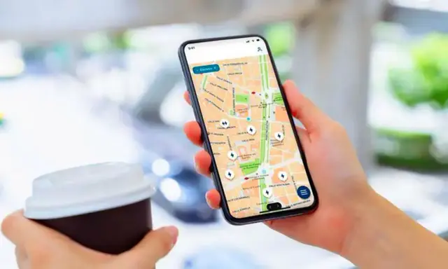 Persona usa un app cargadores eléctricos en su móvil para encontrar puntos de recarga en un mapa.