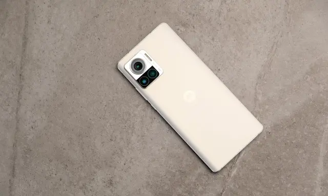 Jasny telefon Motorola edge 30 ultra z potrójnym aparatem na szarym, kamiennym tle.
