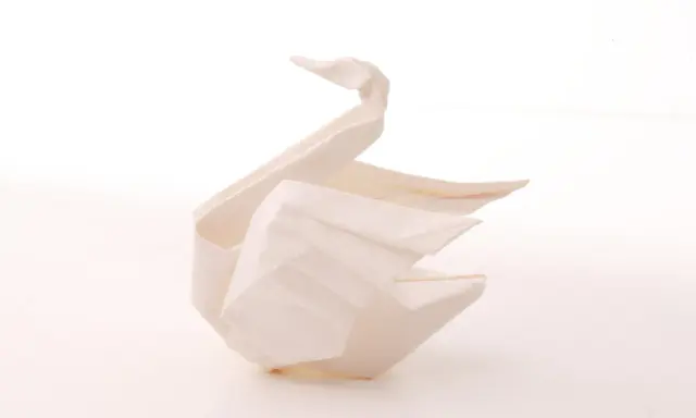 Ein weißer Origami-Schwan, der Eleganz und Reinheit symbolisiert. Die Bedeutung des Origami-Schwan steht für Glück und Treue.
