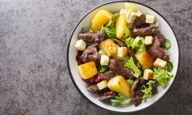 Salade de gésiers savoureuse avec pommes de terre rôties, croûtons et salade verte fraîche. Un délice pour les amateurs de cuisine française.