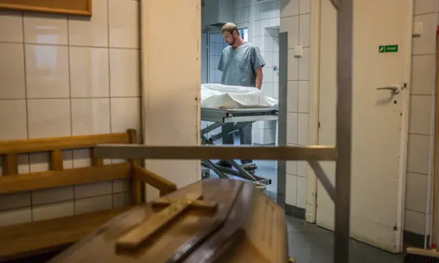 W prosektorium, po sekcji zwłok, pracownik pochyla się nad noszami. Czy po sekcji zwłok można otworzyć trumnę?