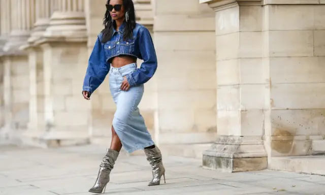 Modella con giacca di jeans corta e gonna lunga, stivali argento scintillanti. Un look che ricorda la moda degli anni '80.