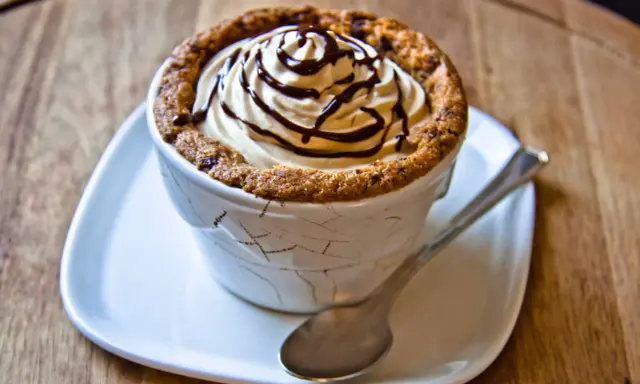 Un délicieux dessert dans une tasse en cookies, garni de crème fouettée et de sauce au chocolat.