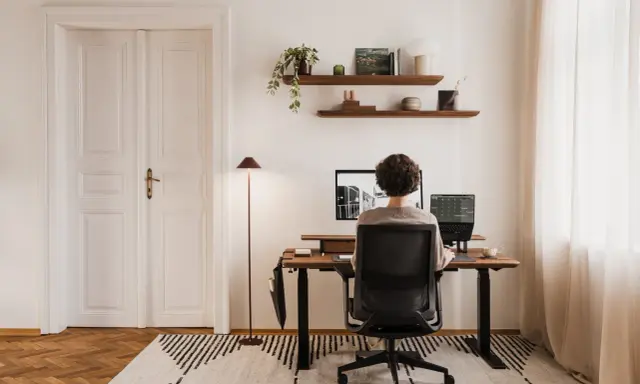 Un espace de travail épuré, avec une personne assise à son bureau, créant le bureau idéal.