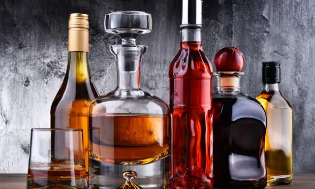 Karafka z koniakiem i inne butelki z brandy na drewnianym blacie.