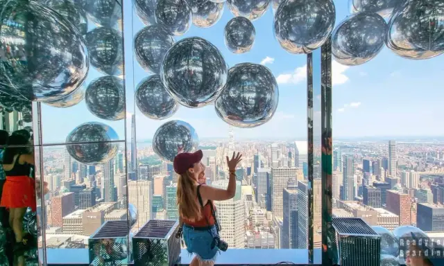 Kobieta cieszy się widokiem z Summit One Vanderbilt, otoczona lśniącymi kulami.