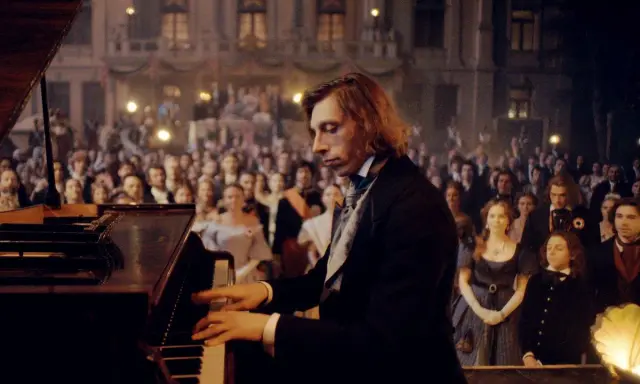 Młody Fryderyk Chopin gra na fortepianie przed zgromadzoną publicznością.