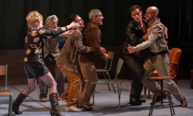 Scène de théâtre tendue. Des hommes se disputent, leurs gestes évoquent une lutte. La scène rappelle la conjugaison du verbe "aboyer" dans un moment de tension.
