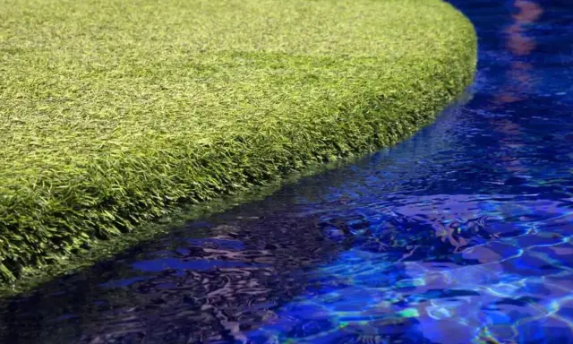 A vibrant green artificial grass island floats in a bright blue pool. The question of will chlorine kill grass is answered by this synthetic turf, unaffected by the water.