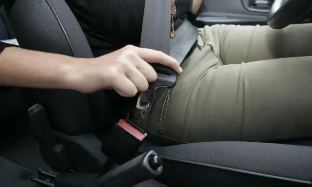 Persona abrochando el cinturón de seguridad. Recuerda, el cinturón de seguridad debe ir siempre abrochado para tu protección.