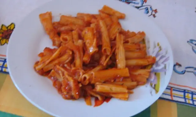 Penne rigate w bogatym sosie pomidorowym, podane na białym talerzu. Pyszny obiad gotowy!