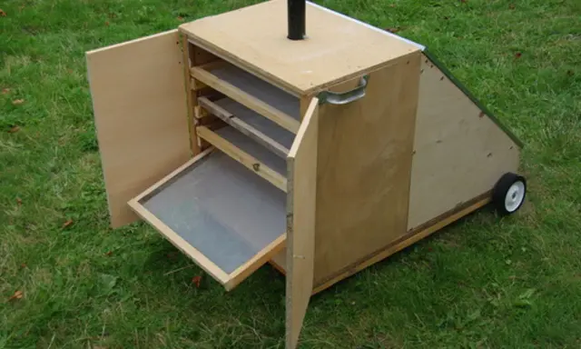 Un sechoir solaire diy en bois, avec des étagères et une porte ouverte sur un tamis. Idéal pour sécher des herbes ou des fruits au soleil.