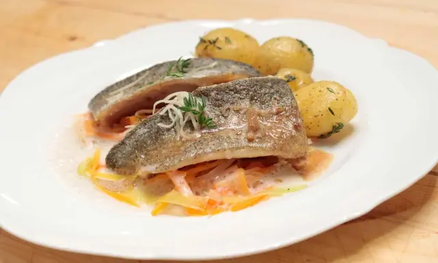 Zartes Forellenfilet braten, serviert mit kleinen Kartoffeln und julieniertem Gemüse in einer leichten Sauce. Ein Genuss!