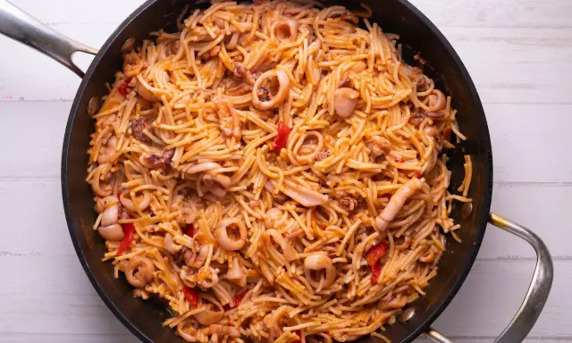 Fideuà de marisco en paellera, con fideos finos, calamares y pimientos rojos. ¡Perfecta para aprender como hacer fideuà!