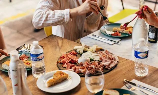 Un plateau de charcuterie et fromages, une spécialité provençale, partagé autour d'une table ensoleillée.
