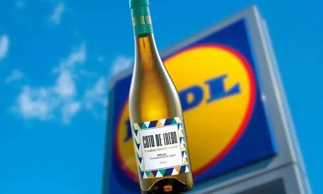 Botella de vino blanco Coto de Ibedo con etiqueta colorida, frente a un cartel de Lidl.