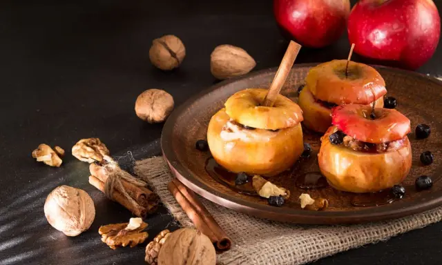 Deliciosas manzanas asadas con canela, nueces y arándanos, listas para disfrutar.