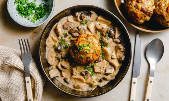 Herzhaftes Gericht: Ein Knödel in cremiger Pilzrahmsoße, garniert mit Schnittlauch. Perfekt, was passt zu Brezenknödel!
