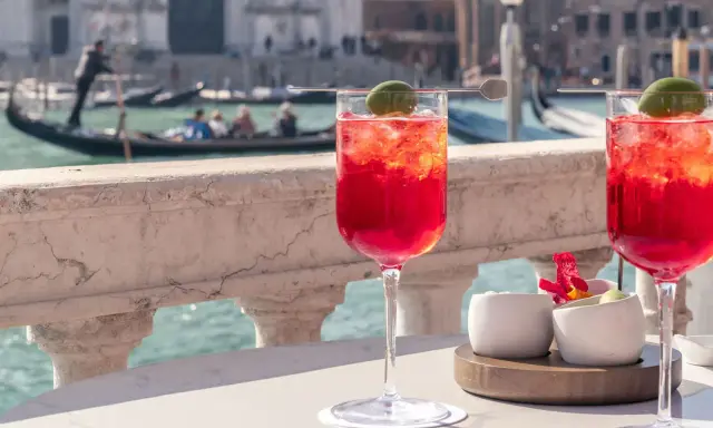 Deux Spritz vénitiens rafraîchissants sur une terrasse avec vue sur les canaux de Venise et les gondoles.
