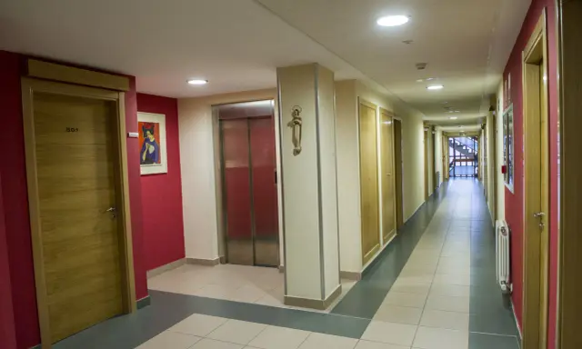 Pasillo de la residencia Laboure con puertas de madera, un ascensor y una pintura.