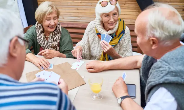 Seniorzy grają w karty, ćwicząc umysł i poprawiając pamięć.