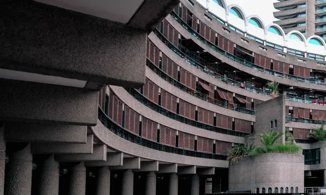 Edifici curvi in cemento con persiane in legno al Barbican Centre. Un'architettura iconica che si staglia nel cielo.