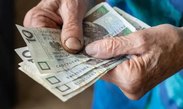 Dłonie seniora trzymają banknoty 10 zł. Kto może liczyć na 500 plus dla seniora?