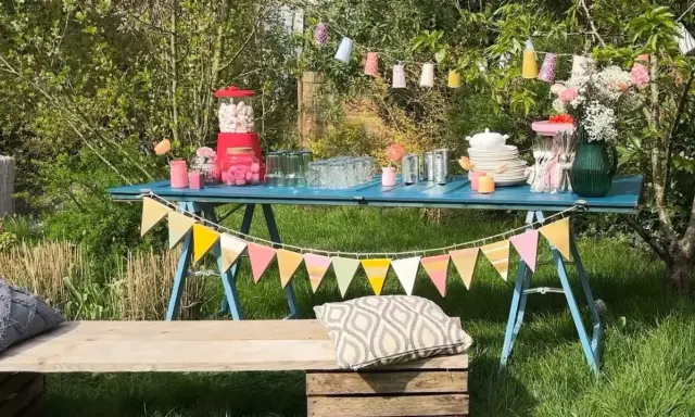 Une table bleue dressée pour une deco garden party à faire soi même, avec guirlandes, bonbons et fleurs.