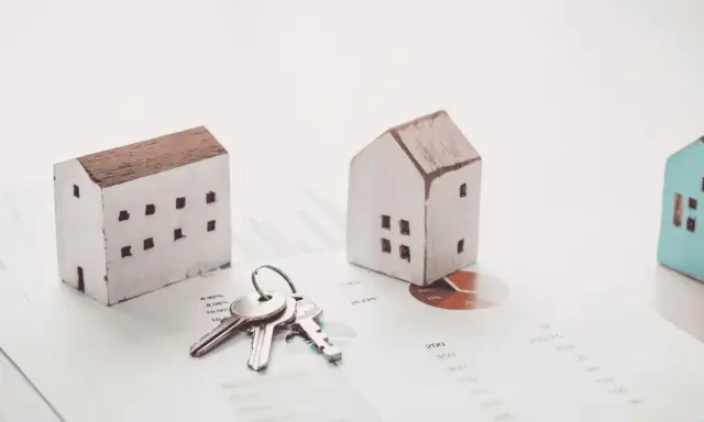 Maquetas de casas y llaves sobre gráficos financieros. El arte 17 lau sugiere una inversión inmobiliaria.