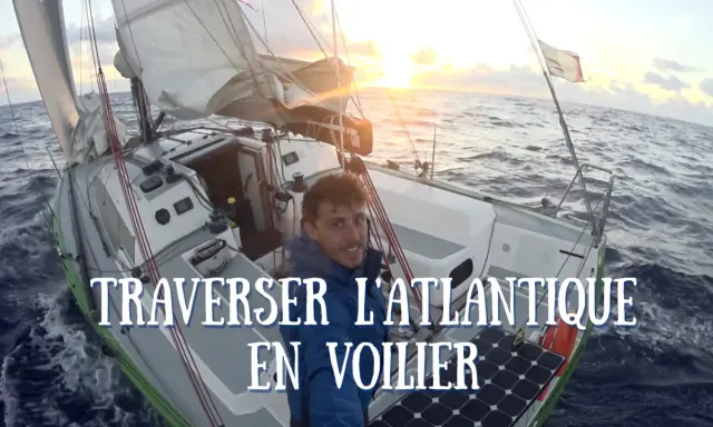 Un homme souriant sur un voilier en pleine traversée de l'Atlantique. Le soleil se lève, illuminant les voiles. Quel voilier pour traverser l'Atlantique ? Celui-ci semble parfait.