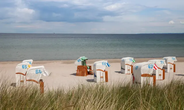Plaża z koszami plażowymi, jakby to były luksusowe hotele w pałacach nad morzem.