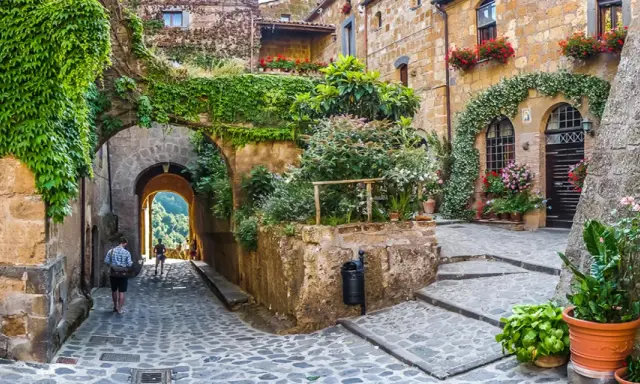 Un vicolo fiorito in uno dei 10 borghi più belli d'Italia, con archi coperti di edera e scorci panoramici.