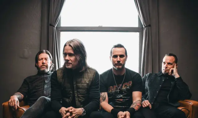 Alter Bridge Sverige: bandmedlemmar sitter på en soffa framför ett fönster.
