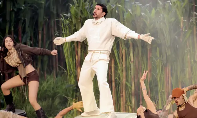 Bad Bunny's iconic bad bunny super bowl outfit, a white ensemble with a "64" on the sweatshirt, stands out against a backdrop of tall green stalks.