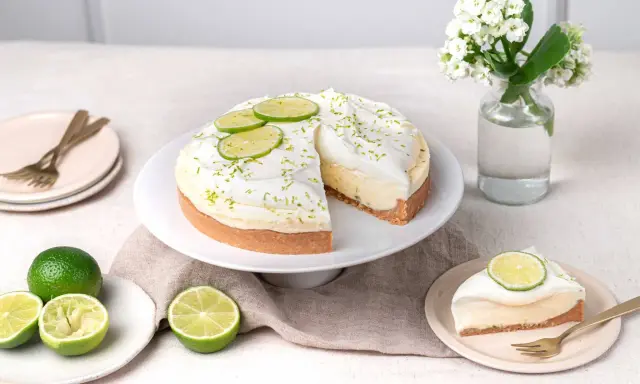 Un cheesecake au citron vert, garni de crème fouettée et de fines tranches de citron vert. Le fromage idéal pour un cheesecake est crémeux et légèrement acidulé.