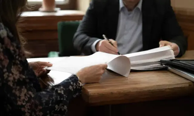 Kobieta i mężczyzna przy biurku przeglądają dokumenty. Sprawa alimentów, gdy nie płaci alimentów kiedy do komornika, wymaga analizy papierów.