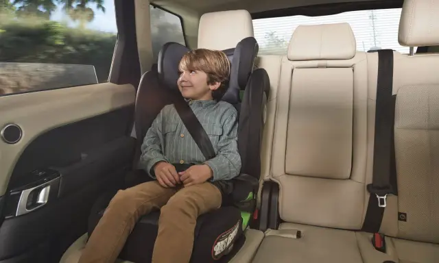 Niño sonriente en una silla de coche grupo 3 edad, viajando seguro y cómodo en el asiento trasero de un vehículo.