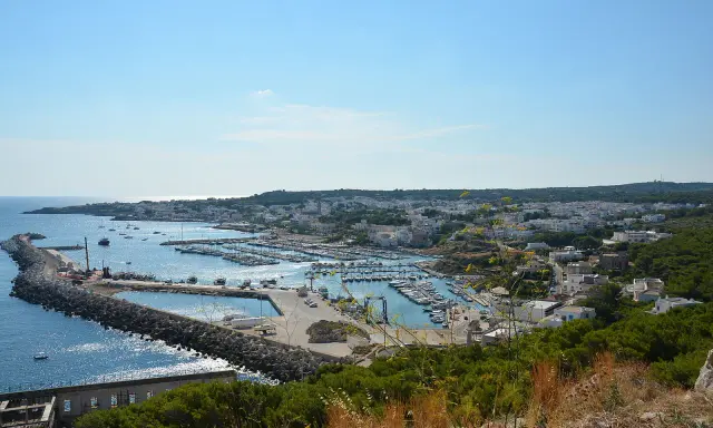 Vista panoramica del porto turistico di Santa Maria di Leuca, in provincia di Lecce, con numerose barche ormeggiate e la città bianca sullo sfondo.