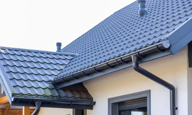 Szary dach z dachówki ceramicznej, idealny do obliczenia dachówka ceramiczna cena za m2. System rynnowy odprowadza wodę.