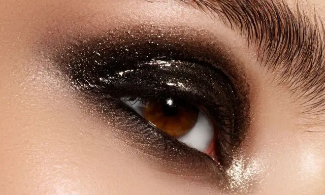 Ojo con un espectacular maquillaje ahumado marrón con brillos intensos y pestañas largas.