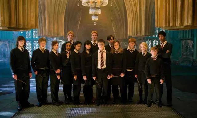 Grupa uczniów z domu Hufflepuff, w tym Harry Potter, stoi w eleganckiej sali.