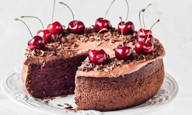Gâteau chocolat cerise, riche et moelleux, décoré de cerises fraîches et de copeaux de chocolat. Un délice gourmand.