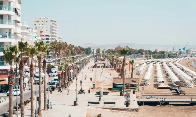 Promenada w Larnace z palmami, białymi budynkami i plażą pełną leżaków. Idealne miejsce, by zobaczyć, co oferuje Larnaka.